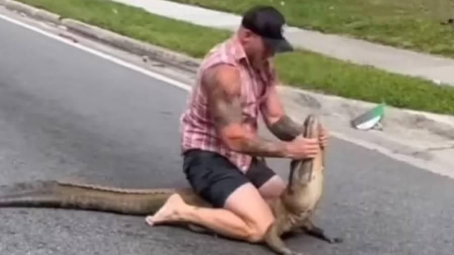 مصارع يقبض بيديه على تمساح